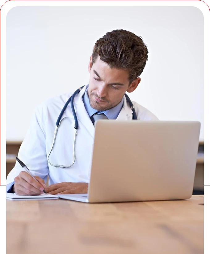 Cardiologist in the clinic writing something in front of a laptop